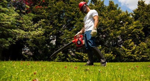 Homem usando um Soprador de Folhas da Toyama para limpar seu jardim.