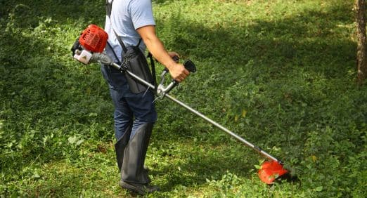 Homem roçando a grama com uma Roçadeira da Toyama.