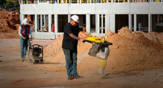 homem usando um compactador em um canteiro de obras